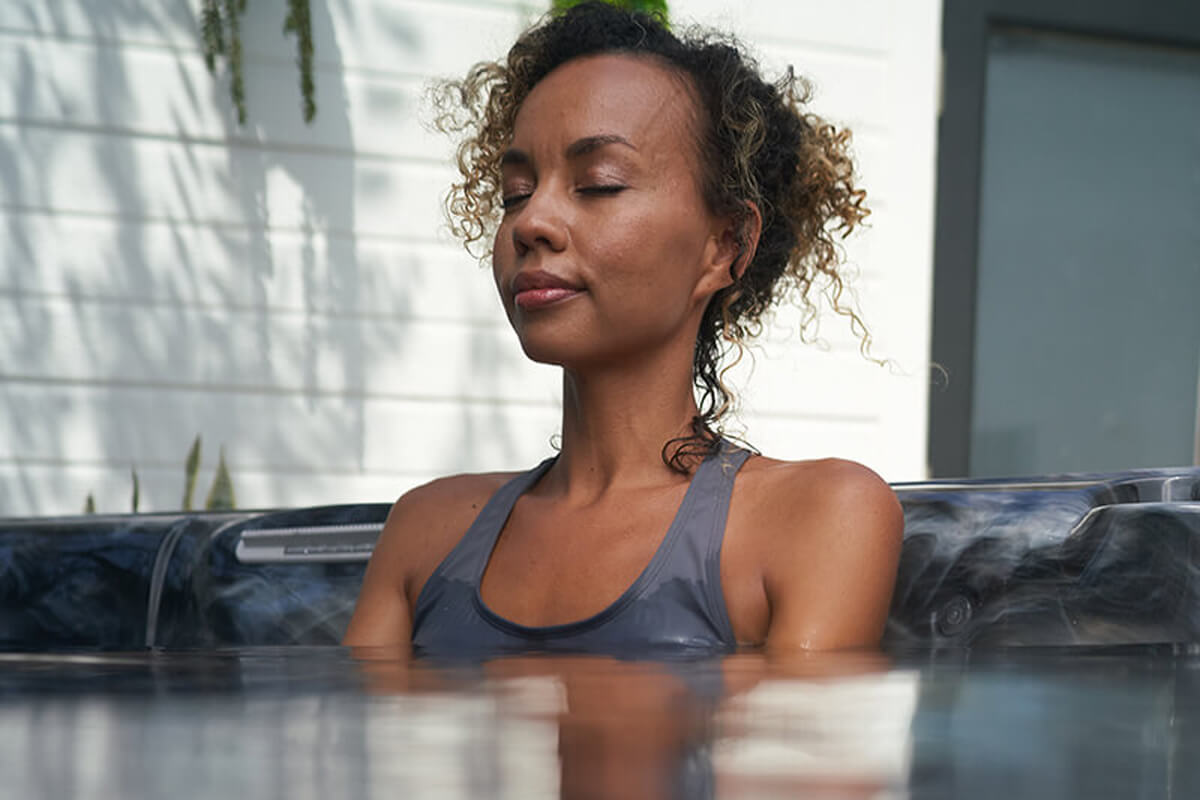 A woman seated in calm water enjoys the relaxing benefits of soaking in a hot tub.