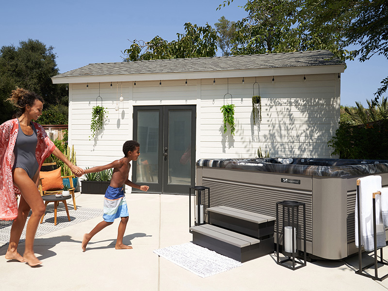  A mother and son are running towards a hot tub on a sunny afternoon.