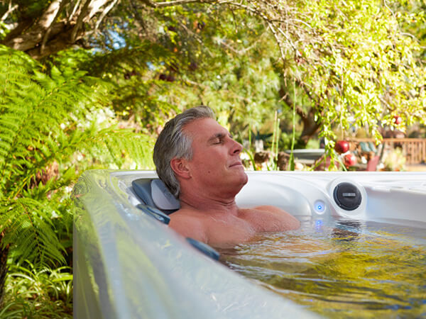 An older man relaxes and enjoys a bubbly soak in a luxurious hot tub. Relaxing in your hot tub can lower stress and boost immunity, promoting overall well-being.