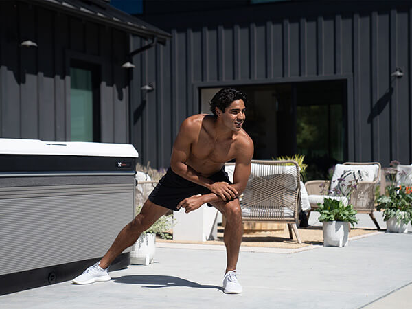 A man working out in an outdoor setting near a Caldera Spas' Utopia Hot Tub.