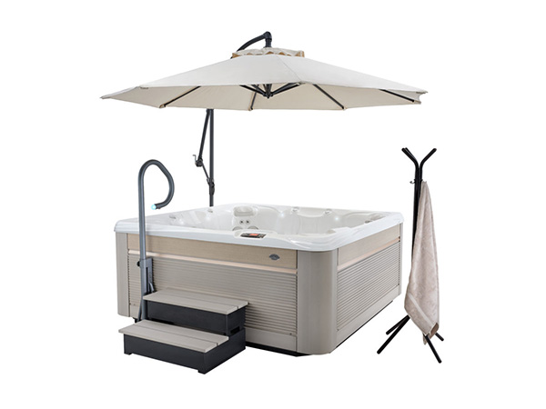 Caldera Paradise 2019 Reunion in Artic White sits next to a sunshade, steps, and a towel rack. The sunshade is attached to a pole extending from the side of the hot tub.