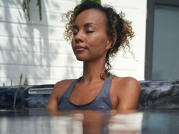 A woman seated in calm water enjoys the relaxing benefits of soaking in a hot tub.